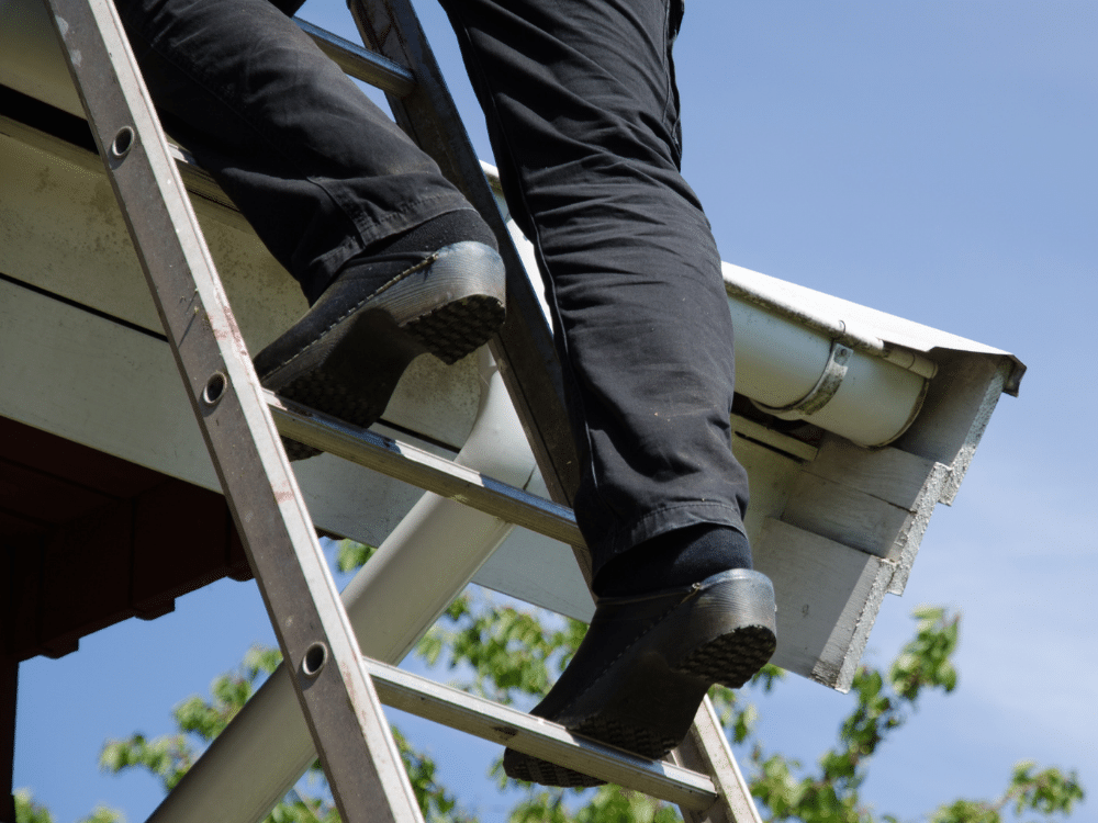 Insurance adjustor climbs a ladder to inspect for storm damage