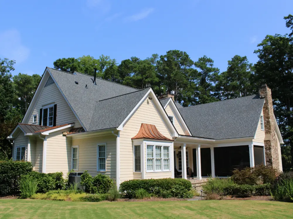 Luxury home in Cary, NC with cream siding, bronze bay window accents, and a CertainTeed Landmark Georgetown Gray roof installed by Artisan Quality Roofing