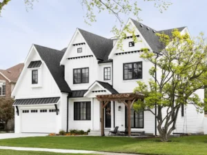 white house style home with white siding, black roof, and black gutters - utilizes complementary color scheme