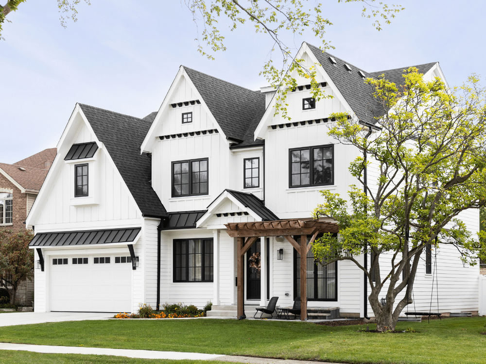 Farmhouse style home with white siding, black roof, and black gutters - utilizes complementary color scheme