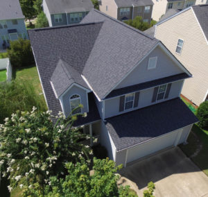 Roof replacement in Raleigh - aerial view of home with blue siding and Landmark Moire Black shingles