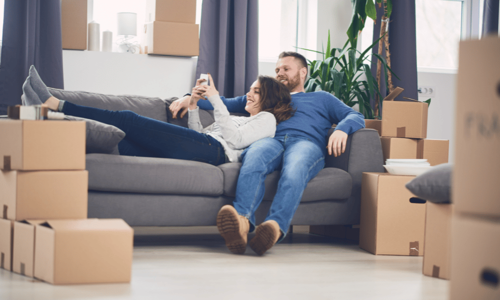 New homeowner couple on couch with moving boxes