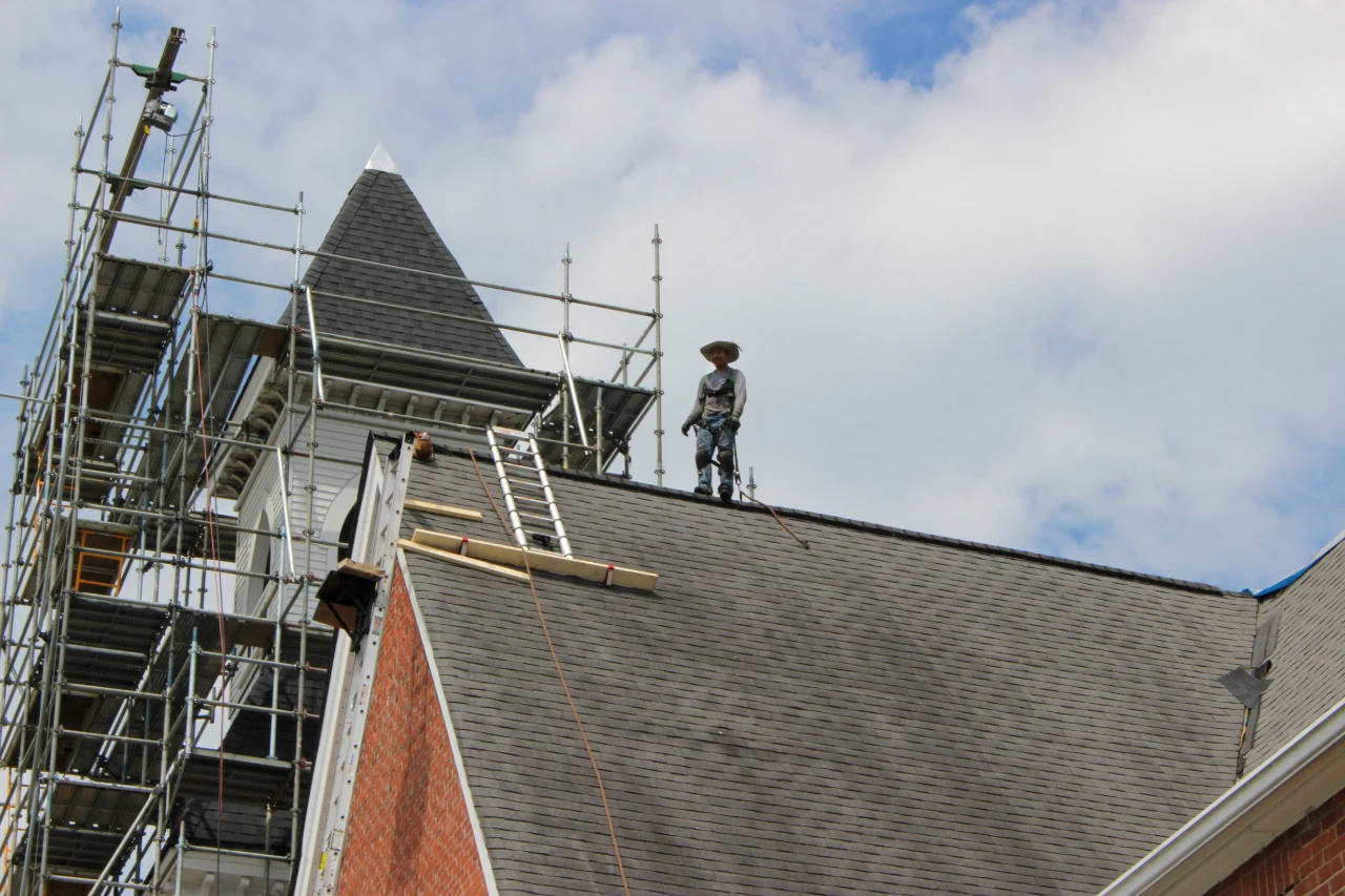 Technician on roof peak getting shingle bundle